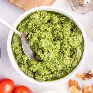 A bowl of pesto with tomatoes and walnuts.