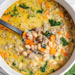 A bowl of soup with beans and spinach.