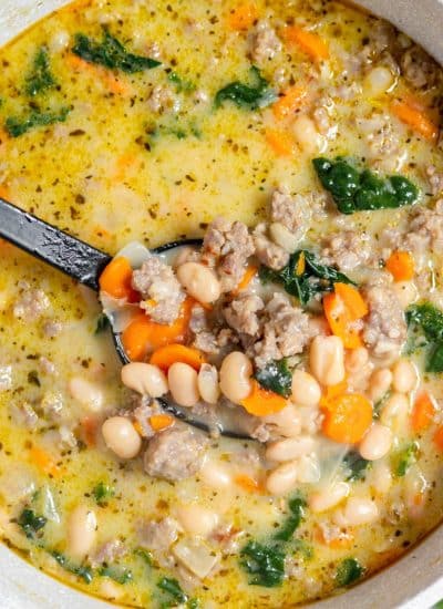 A bowl of soup with beans and spinach.