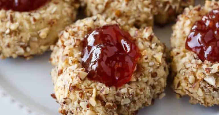 A plate of oatmeal cookies with jam on top.