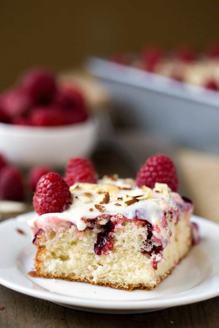 A slice of raspberry cake on a white plate.