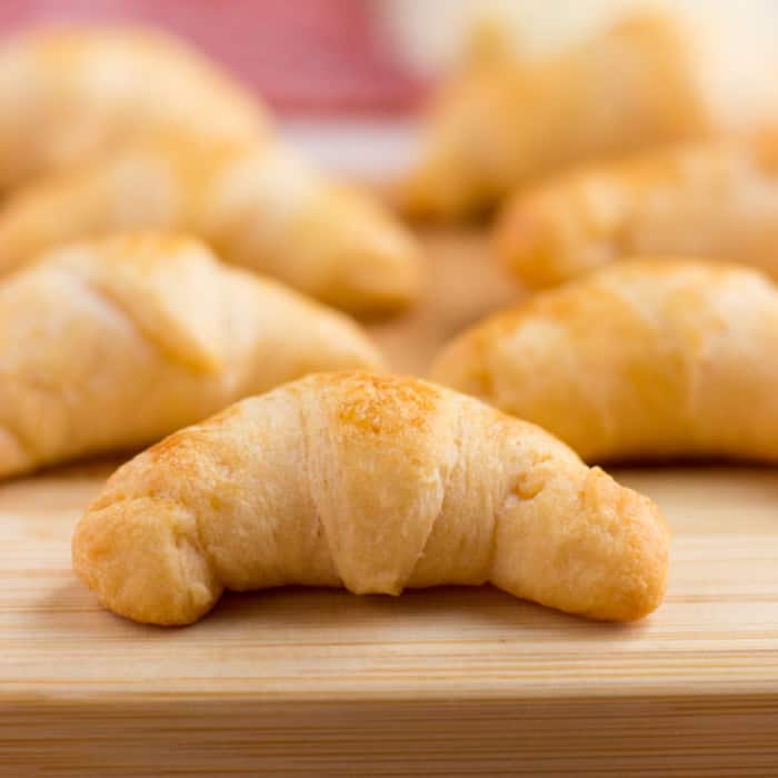 Cheesy croissants on a wooden cutting board.