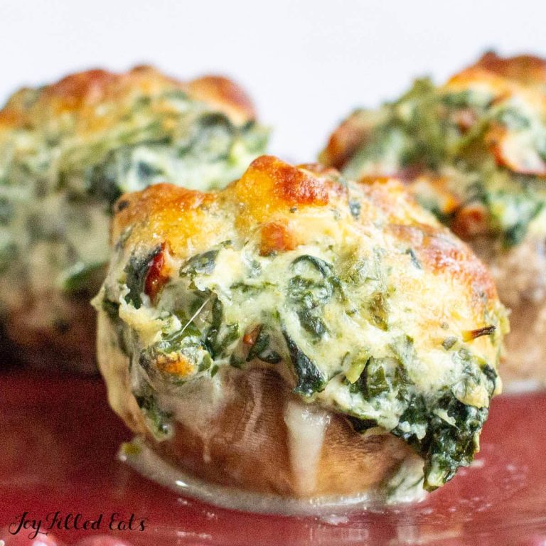 Three stuffed mushrooms with spinach and cheese on a plate.