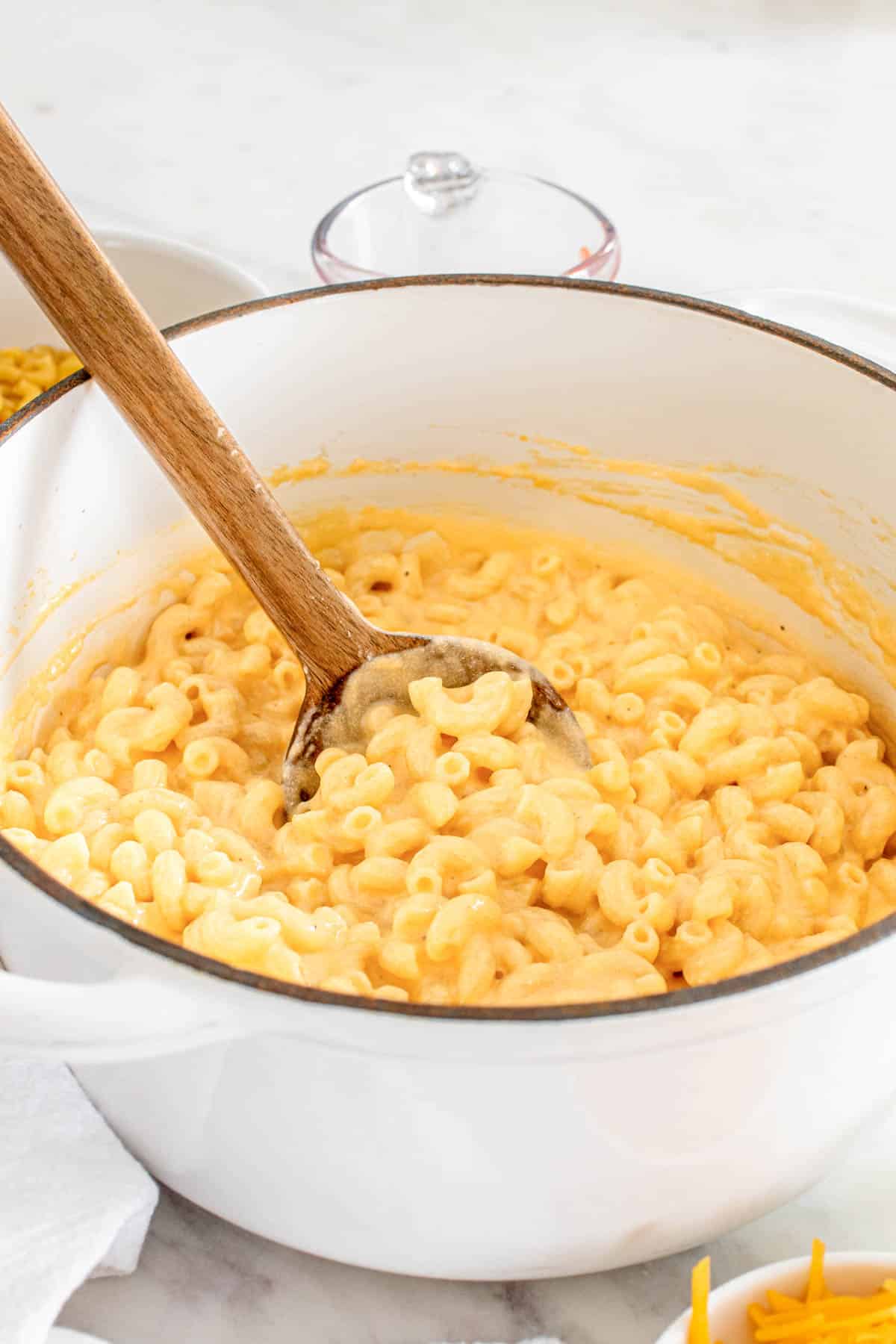 Stovetop macaroni and cheese in a pot with a wooden spoon.