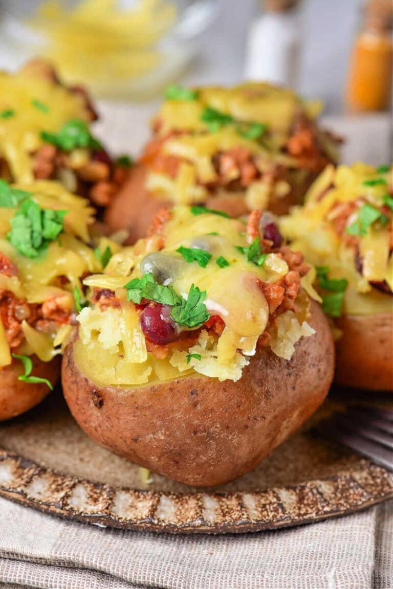 Four stuffed potatoes on a wooden plate.