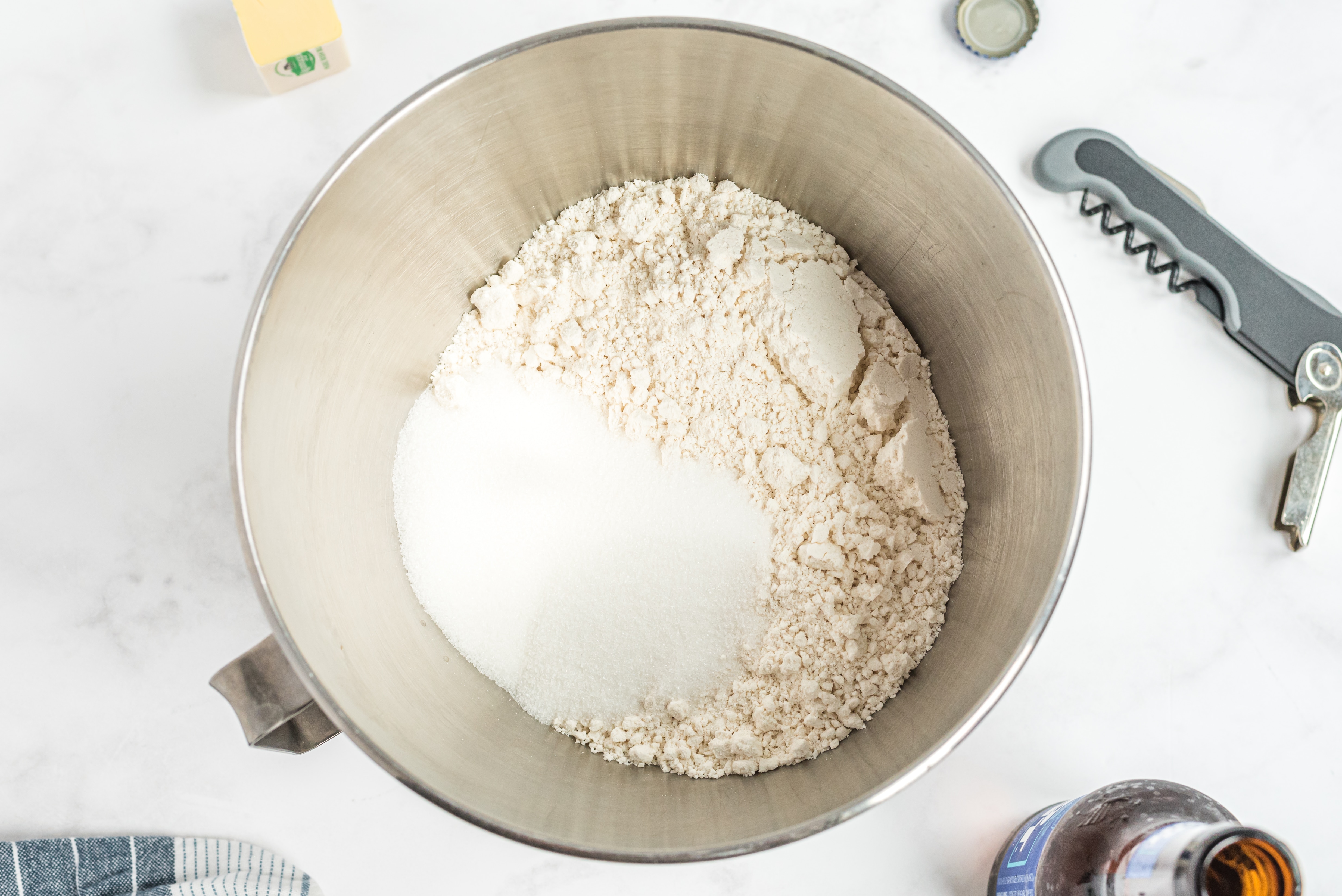 Flour and sugar measured in a metal mixing bowl, baking preparation underway.
