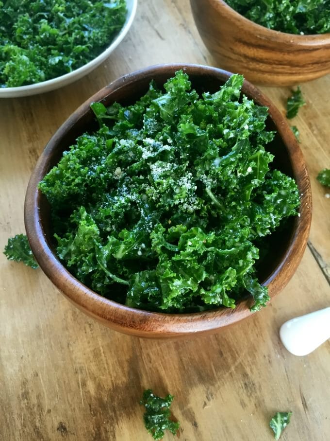 Kale salad in bowls on a wooden table.