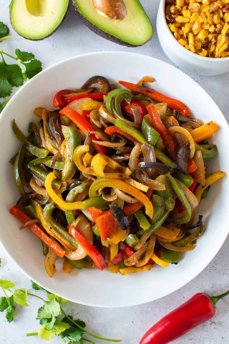 A bowl of mexican fajitas with peppers and avocado.
