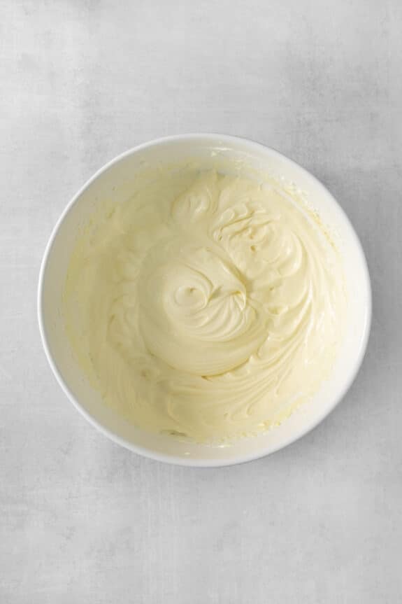 Whipped cream in a white bowl on a gray background, perfect for banana pudding dip.