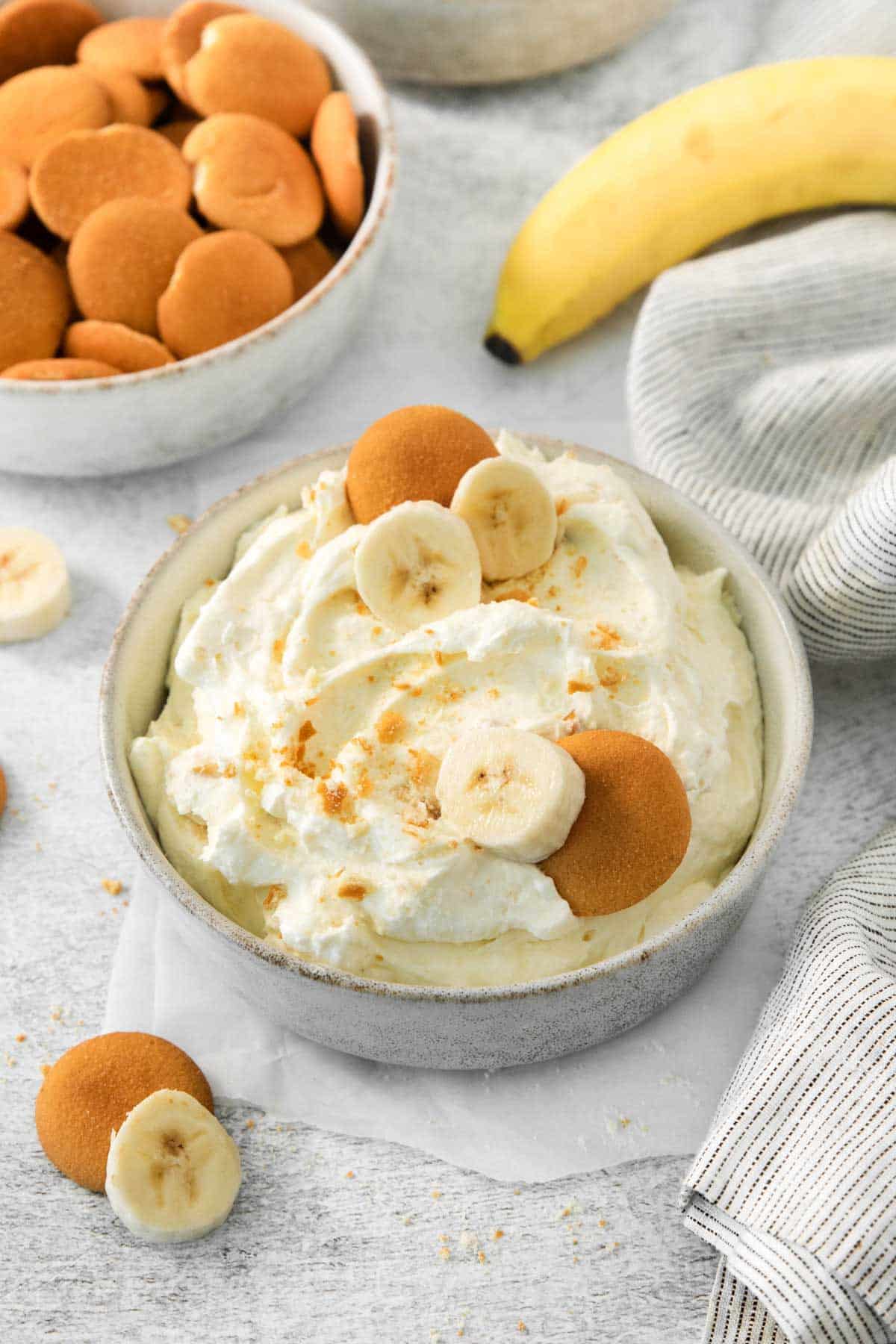 A bowl of banana pudding dip with whipped cream in a white bowl.