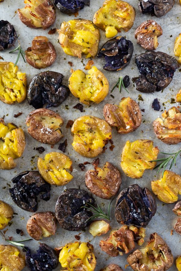 Roasted potatoes with rosemary and thyme on a baking sheet.