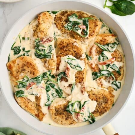 Chicken with spinach and cream sauce in a skillet.