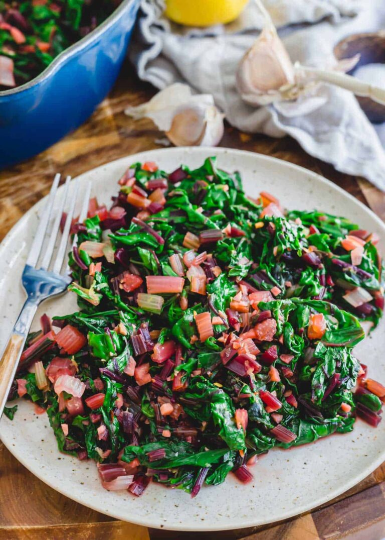 A plate of greens and beans on a wooden table.