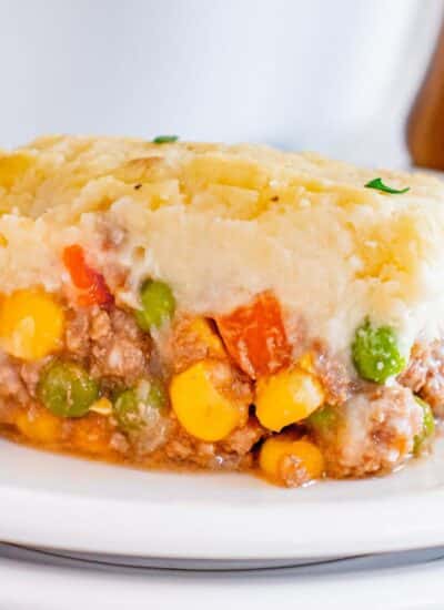 A serving of shepherd's pie, showcasing a layer of mashed potatoes atop a mixture of ground meat and mixed vegetables.