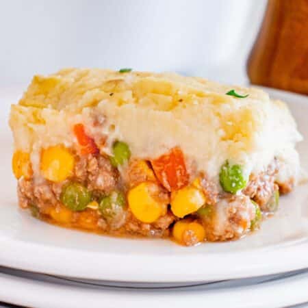 A serving of shepherd's pie, showcasing a layer of mashed potatoes atop a mixture of ground meat and mixed vegetables.