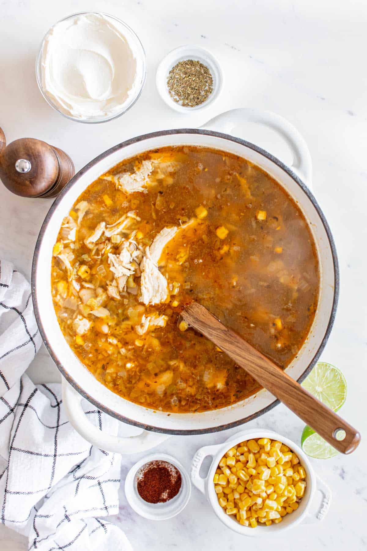 A pot of chicken tortilla soup with ingredients and condiments on the side.