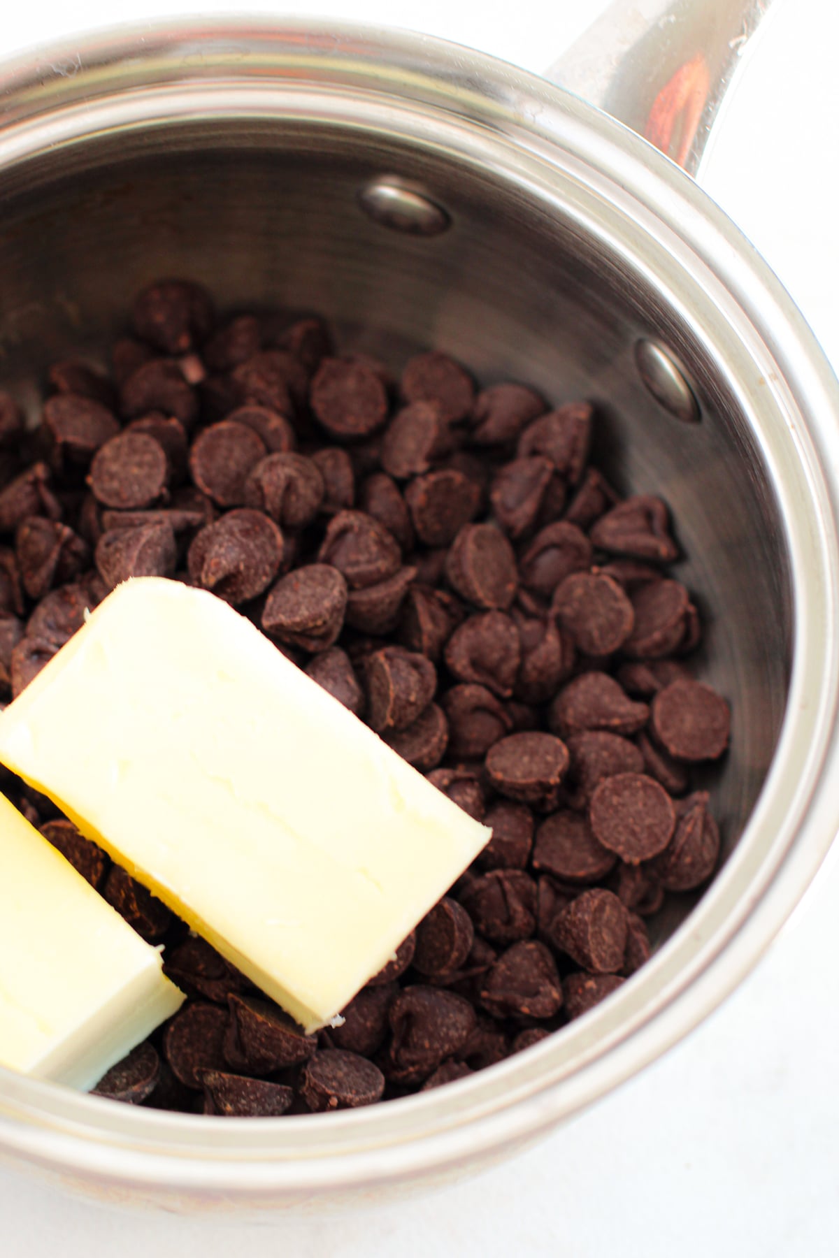 A stainless steel saucepan filled with chocolate chips and two sticks of butter on top for Fudgy Mocha Brownies recipe