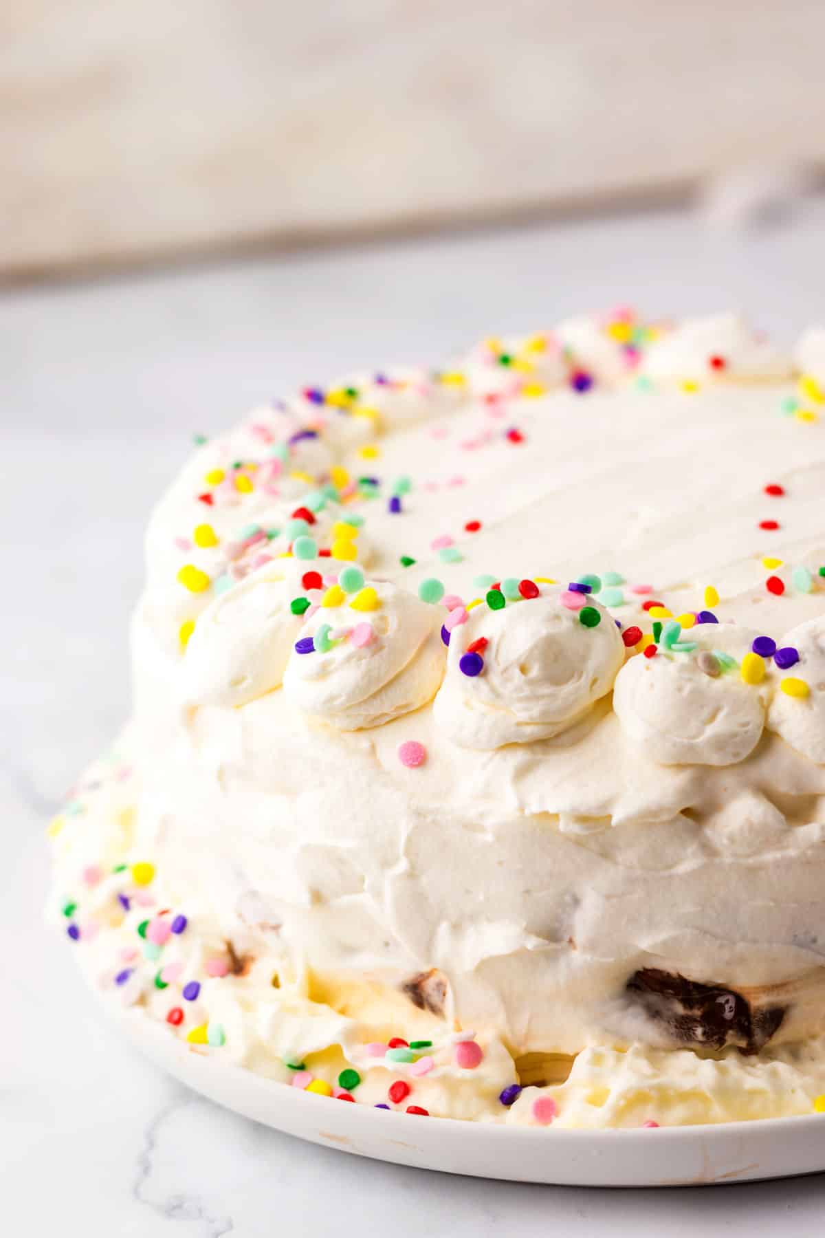 Dairy Queen Ice Cream Cake covered in white frosting with colorful sprinkles, displayed on a white plate against a light background