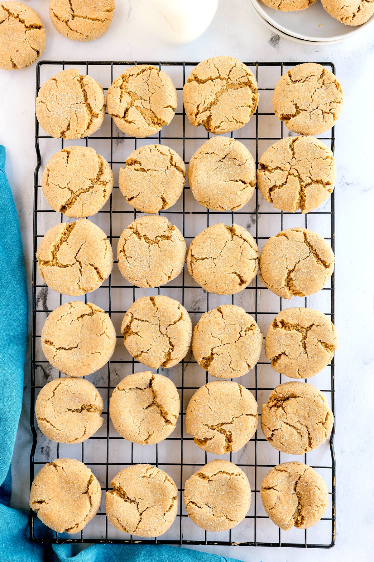 A batch of round, golden Brown Butter Cookies cooling on a black wire rack against a white background.