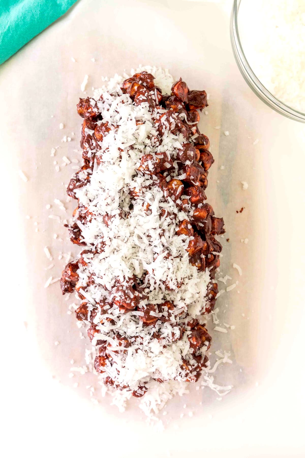 A Church Window Cookies sits on parchment paper, with a glass bowl of shredded coconut nearby.