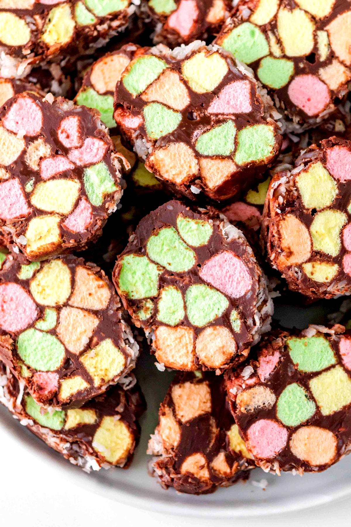 A plate of Church Window Cookies slices with multicolored mini marshmallows and coconut flakes, arranged closely together.