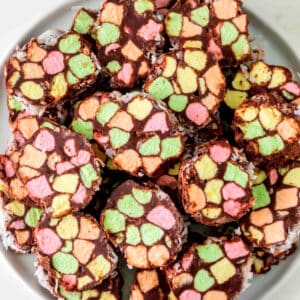 Slices of Church Window Cookies with colorful pastel mini marshmallows are arranged on a white plate.