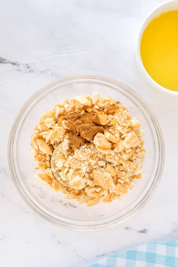The first step in making Ritz Cracker Pie topping is to use a glass bowl with crushed crackers, brown sugar and cinnamon.
