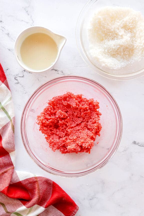 Next process in preparing Christmas Jello Balls is to mix a bowl of coconut to the mixture. A bowl of milk, grated coconut and checkered linen are also seen.