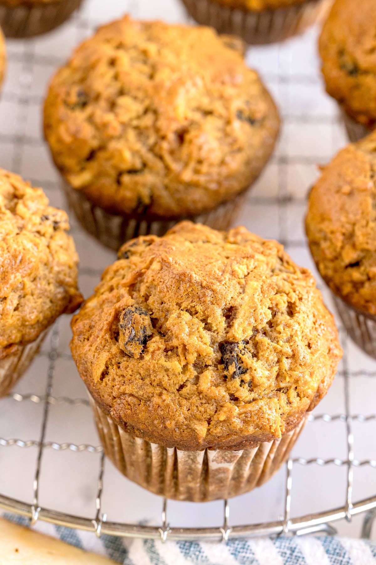 Close-up of freshly baked Morning Glory Muffins with raisins, resting on a wire cooling rack.