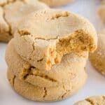 A stack of three brown butter sugar cookies, each coated in sugar, with the top cookie missing a bite.
