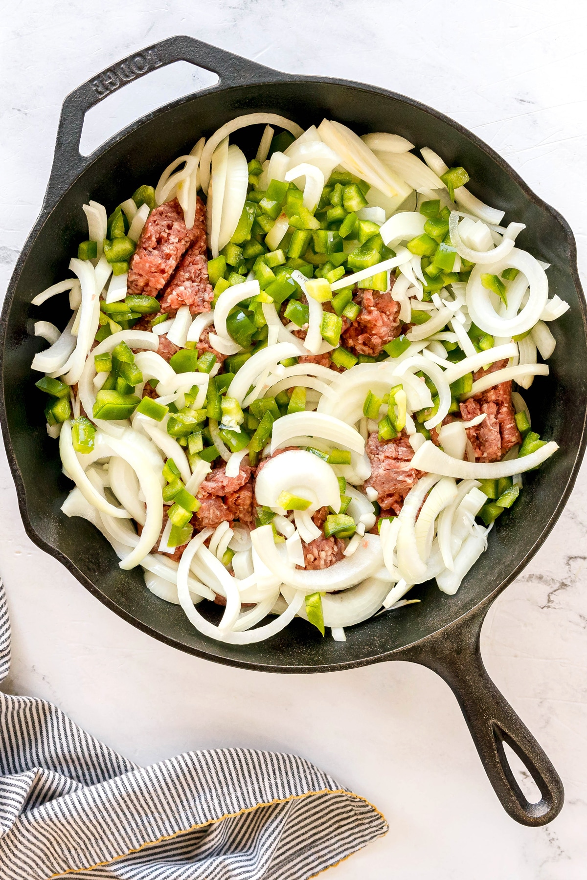 First step in making Texas Hash is to add the ground beef, sliced onions, and chopped green pepper. Cook, breaking up the beef, until it’s fully browned and the vegetables have softened.