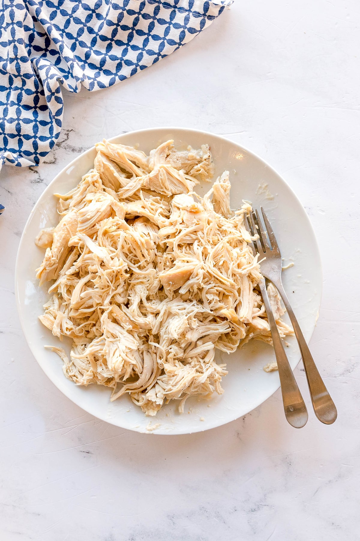 A plate of shredded chicken for Slow Cooker Creamy Italian Chicken recipe.