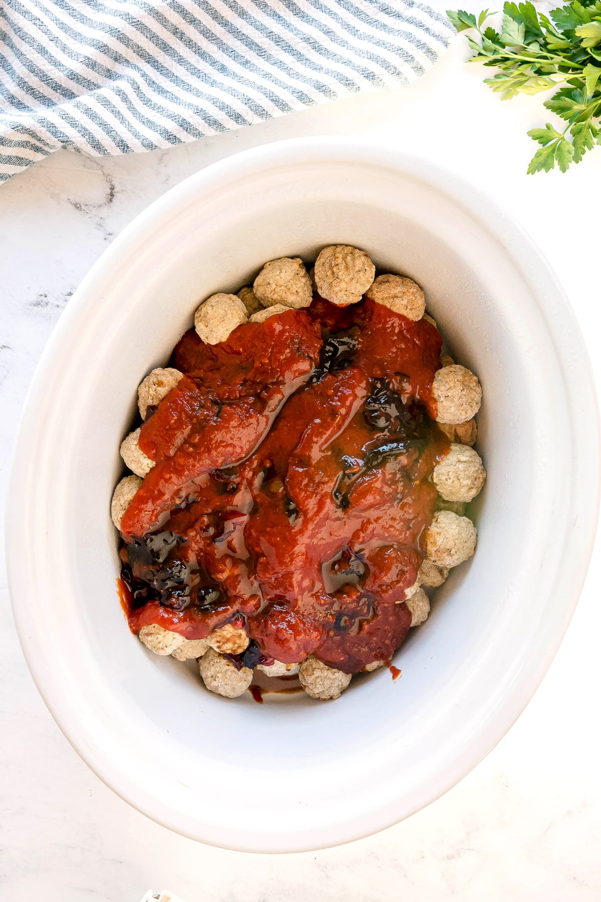 First step in preparing Meatballs with Grape Jelly and Chili Sauce is to use white oval slow cooker and spoon the grape jelly, chili sauce, and Worcestershire sauce directly over the meatballs.