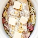 Raw chicken breasts topped with garlic, flour, and butter are placed over sliced red potatoes and shredded cheese in a slow cooker—similar to the savory flavors you love in a Ranch Pork Loin.