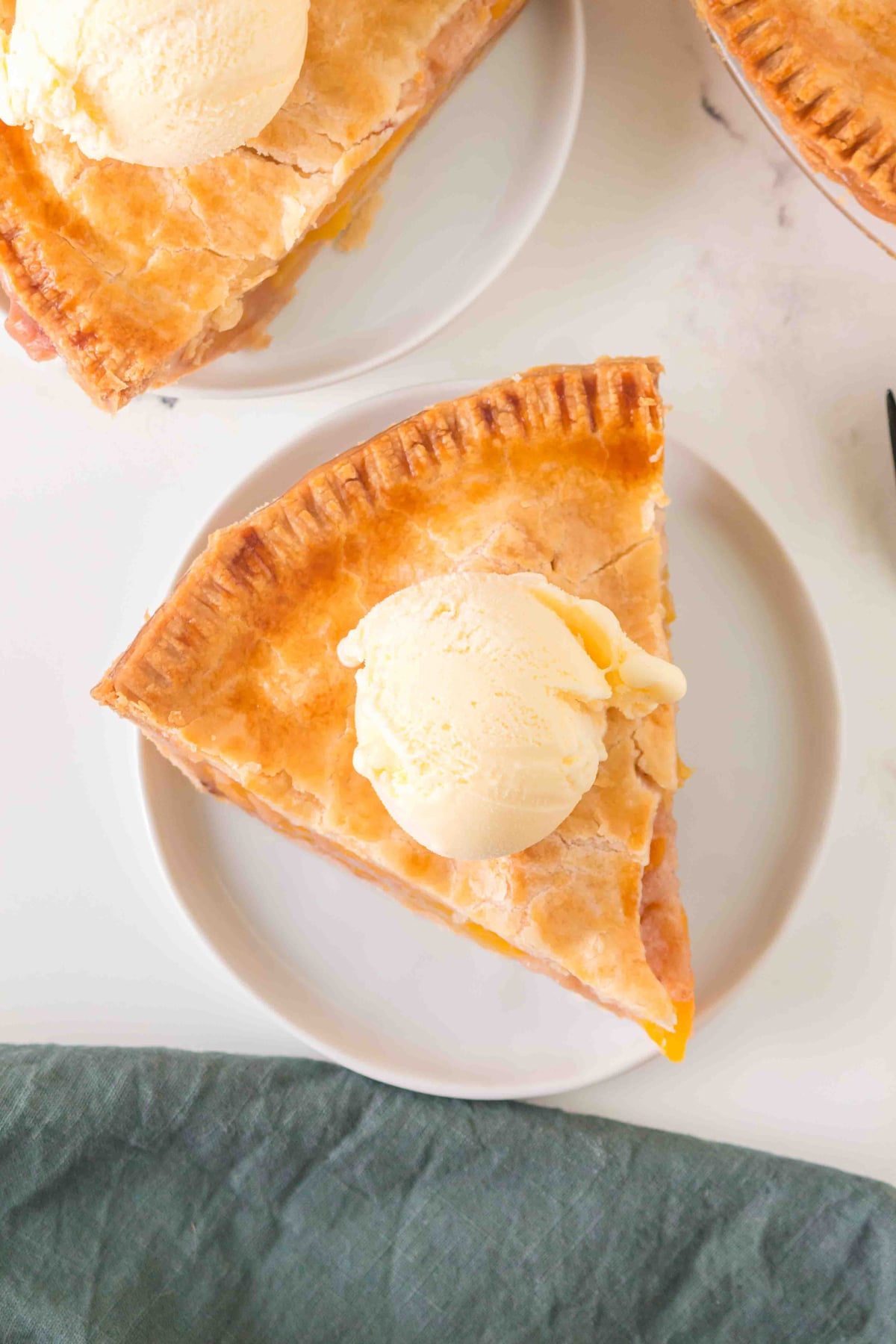 A slice of pie topped with a scoop of vanilla ice cream is served on a white plate.