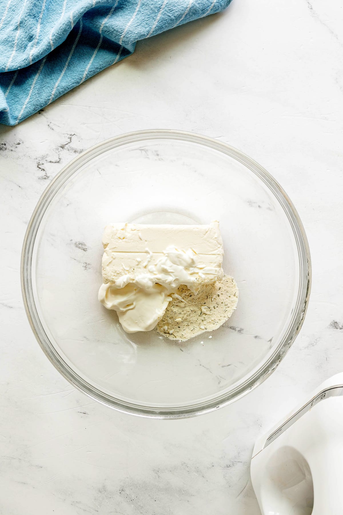 First step in preparing Easy Crack Chicken Pinwheels is to beat the softened cream cheese, sour cream, and ranch seasoning until smooth in a mixing bowl.
