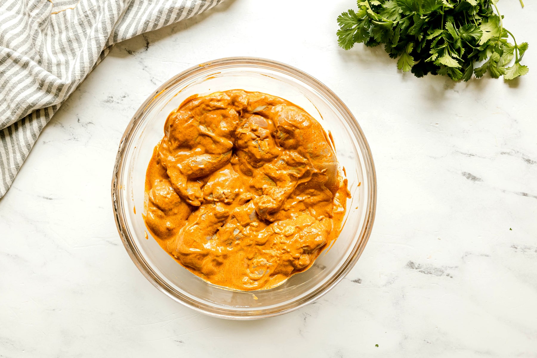 Next step in preparing Butter Chicken is to use a evenly coat the chicken with marinade mixture.