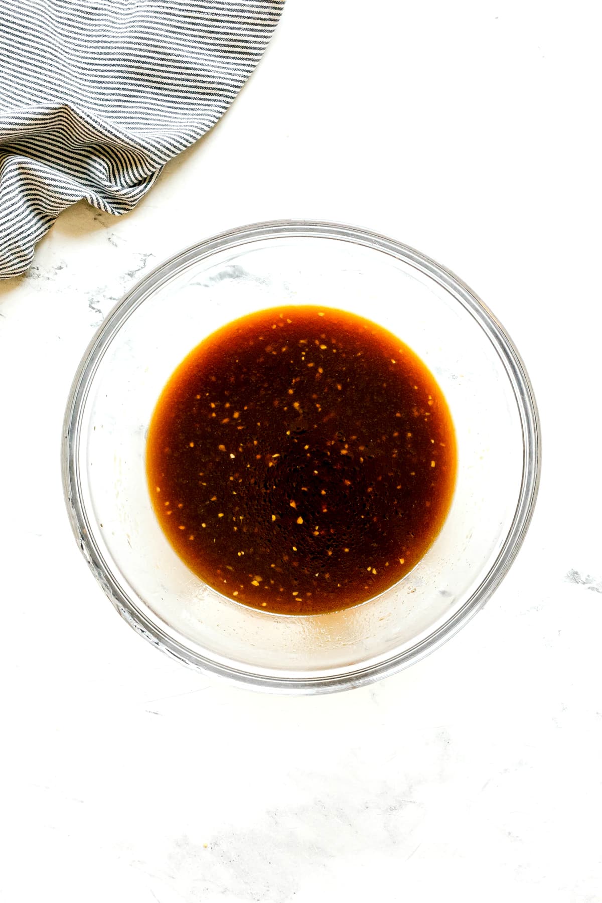 A glass bowl with reserved pineapple juice, ketchup, soy sauce, brown sugar, cider vinegar, ginger, garlic, and sesame oil for Huli Huli Chicken marinade.