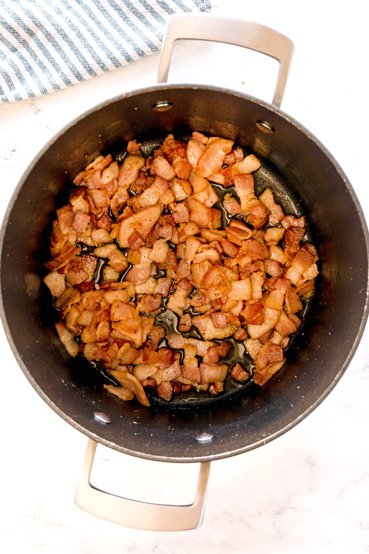 First step in preparing Southern Collard Greens is to add chopped bacon pieces in a pan, cooking and browning it.