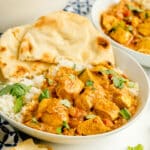 A bowl of Chicken Masala Recipe with white rice, garnished with cilantro, served with naan bread on the side.