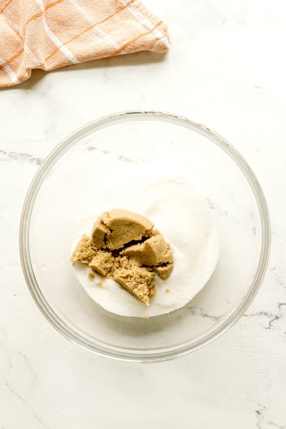 A glass bowl with sugar, brown sugar, on the mixture for Starbucks Pumpkin Bread.