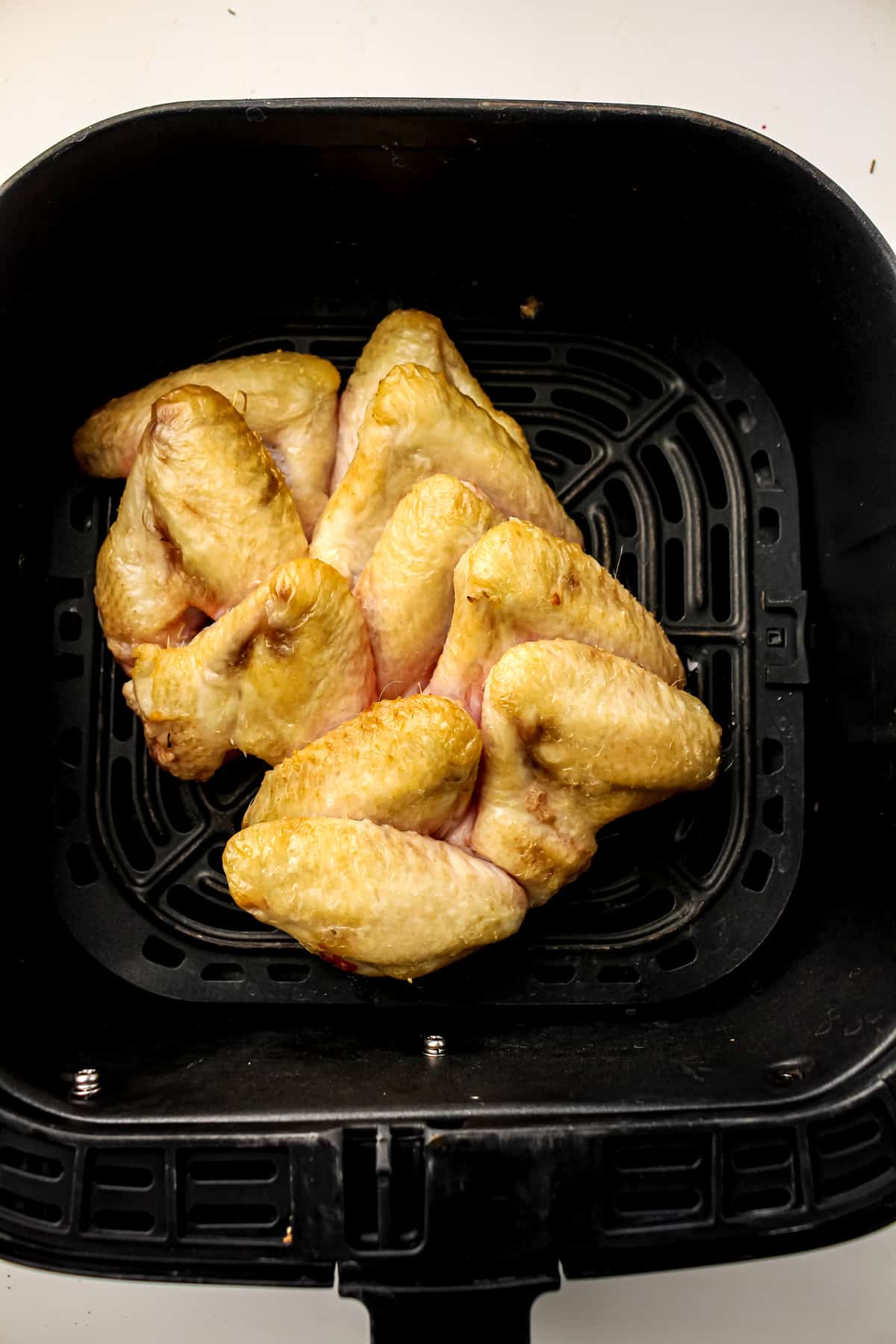Next step in preparing Air Fryer Frozen Chicken Wings is to cook it for 10 minutes to thaw the meat.