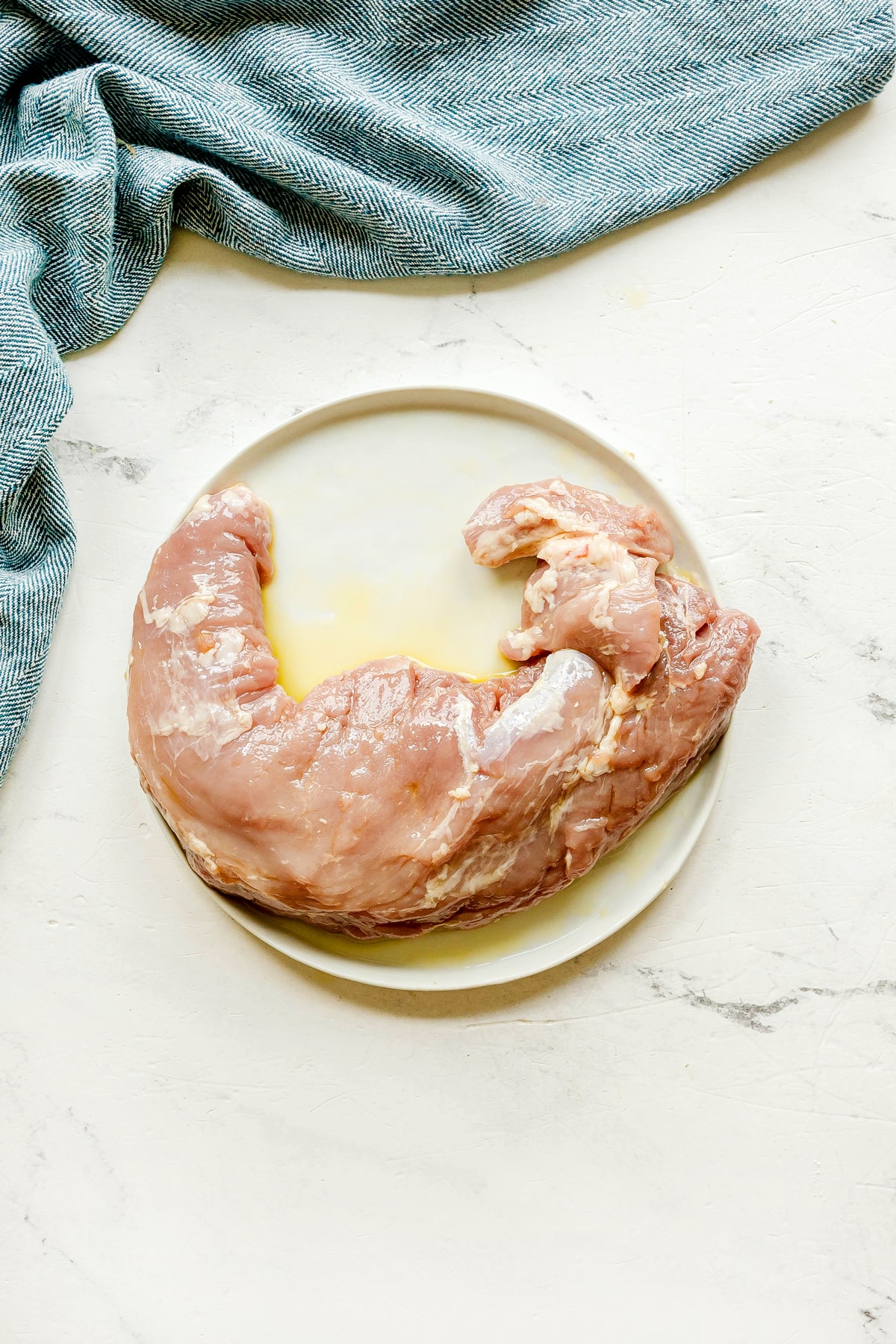 First step in preparing Air Fryer Pork Tenderloin is to remove the silver skin from pork meat and rub an olive oil all over it.