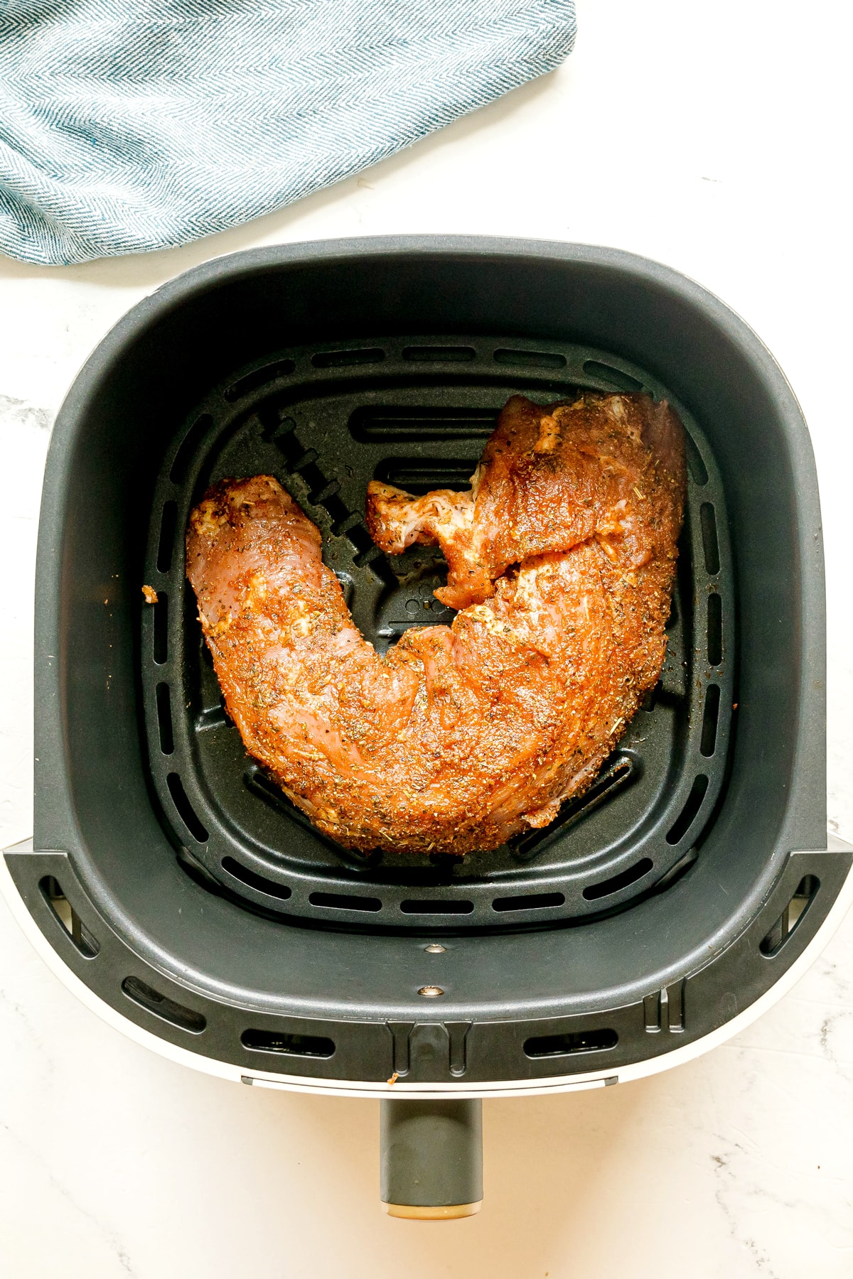 Next step in preparing Air Fryer Pork Tenderloin is to put the seasoned meat in air fryer basket.