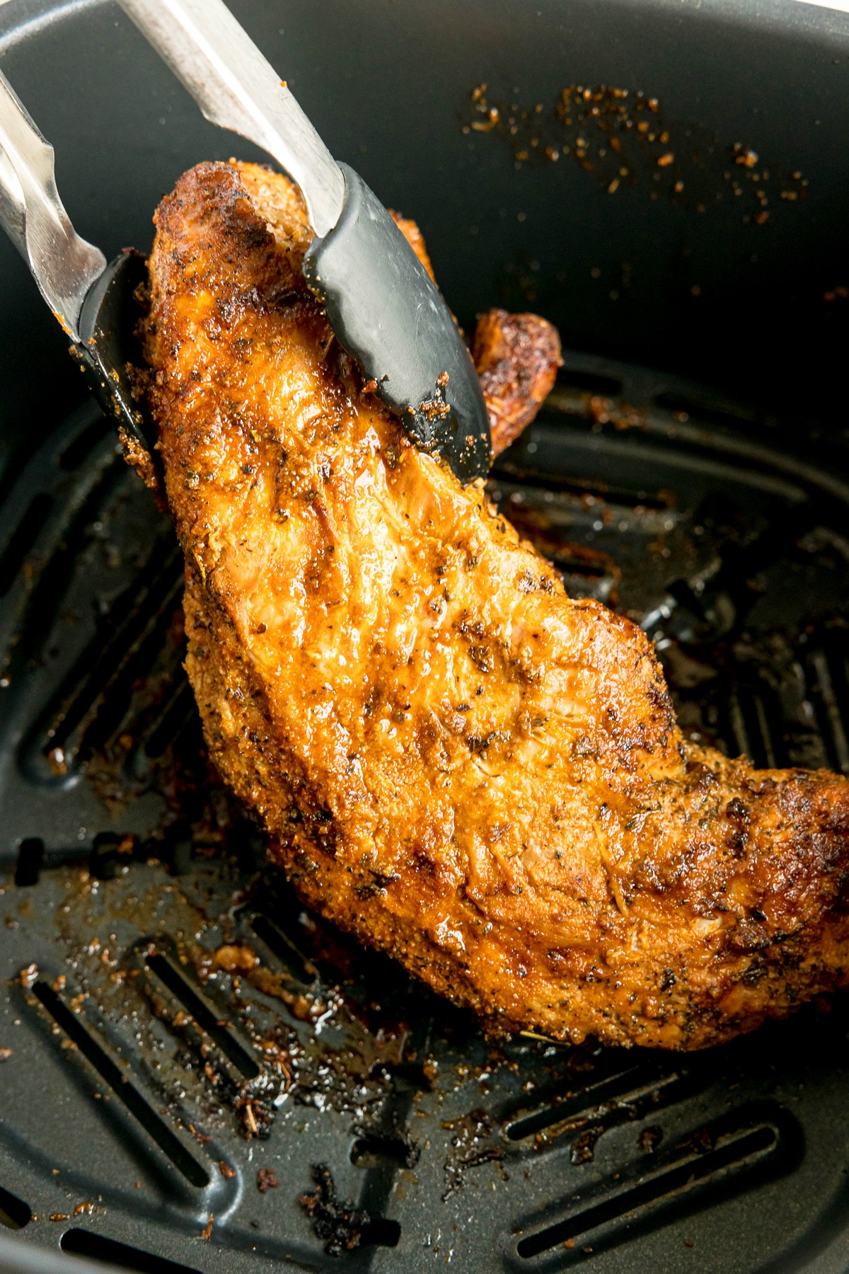A piece of Air Fryer Pork Tenderloin with juices on air fryer basket.