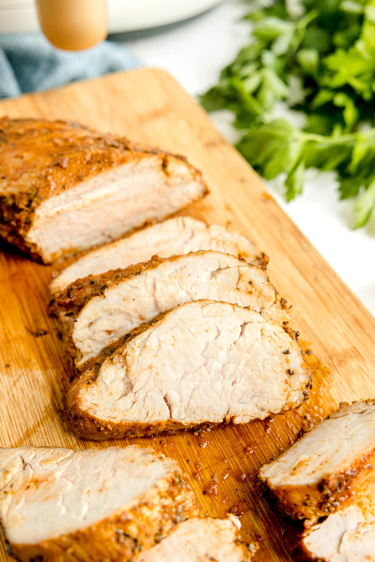 Slices of Air Fryer Pork Tenderloin on wooden board.
