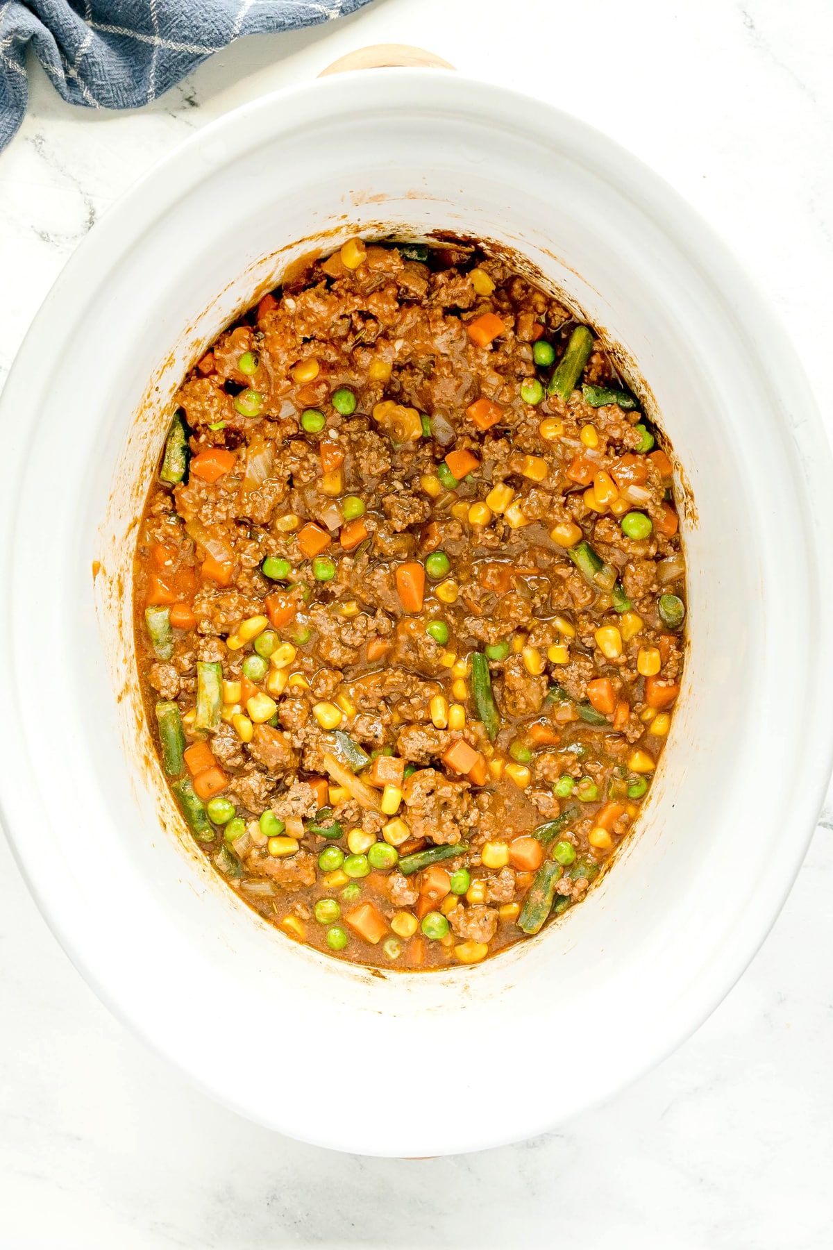 Next step in preparing Crockpot Shepherd's Pie is to add mixed veggies and potatoes to the mixture.