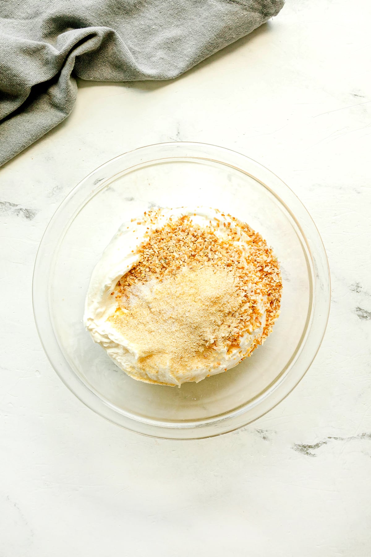First step in preparing French Onion Dip is to use a clear glass bowl and add sour cream, dried minced onion, onion powder, garlic powder, and salt.