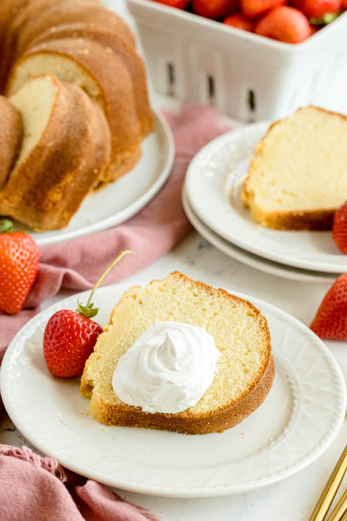 A slice of Paula Deen Pound Cake with frosting on top and strawberry on the side.