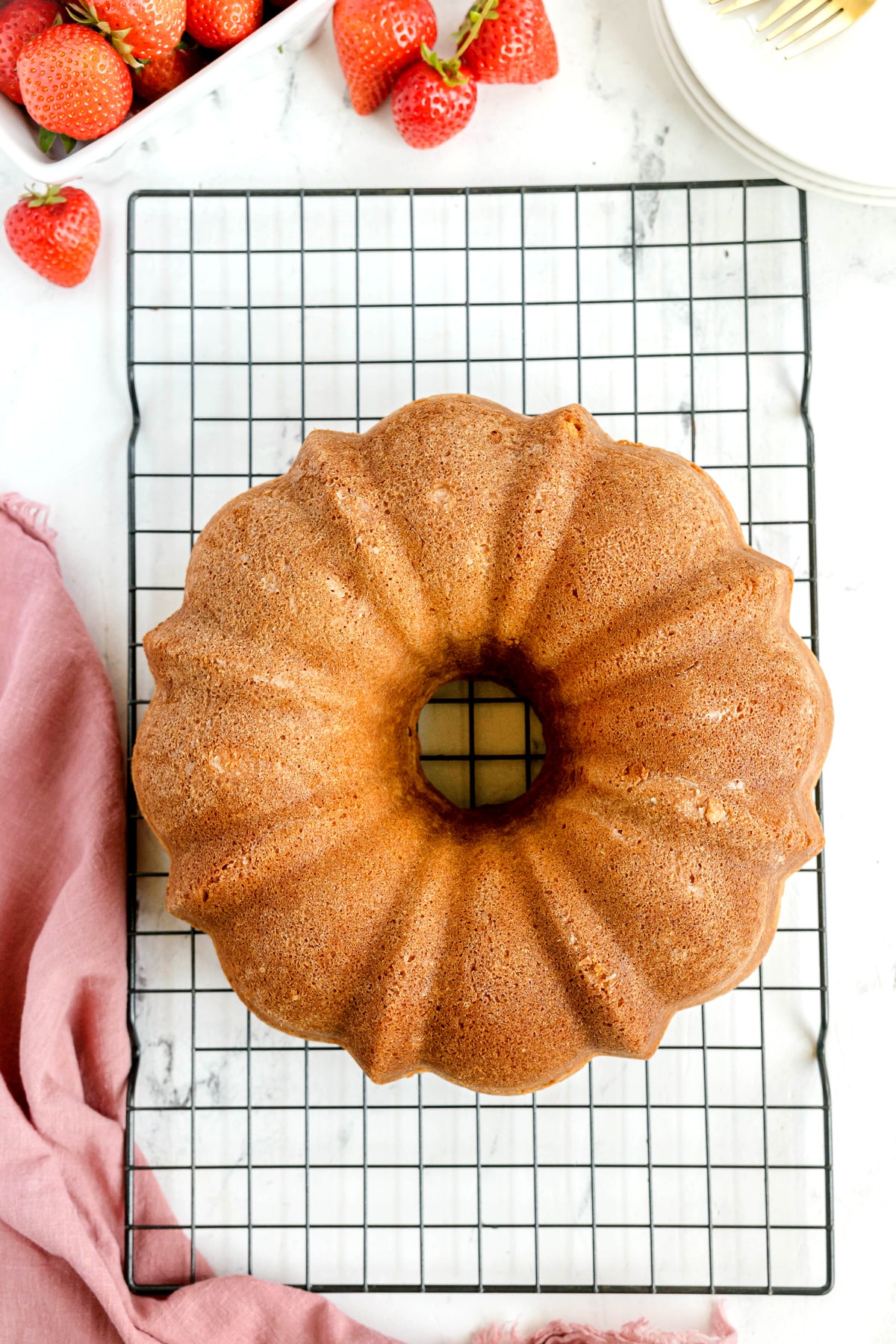 Freshly-baked Paula Deen Pound Cake on top of rack with strawberries and linen on the side
